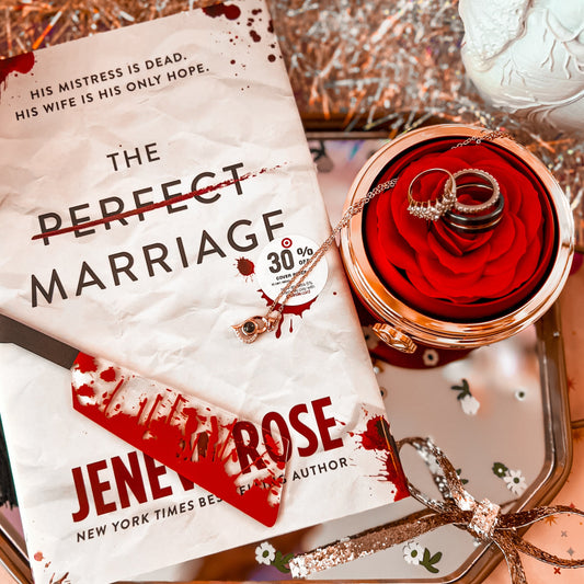 The image shows a acrylic bookmark with a bloody knife design, placed next to a book titled 'The Perfect Marriage' by Jenley Rose. The bookmark is red, and the book cover is white with blood splatter graphics.