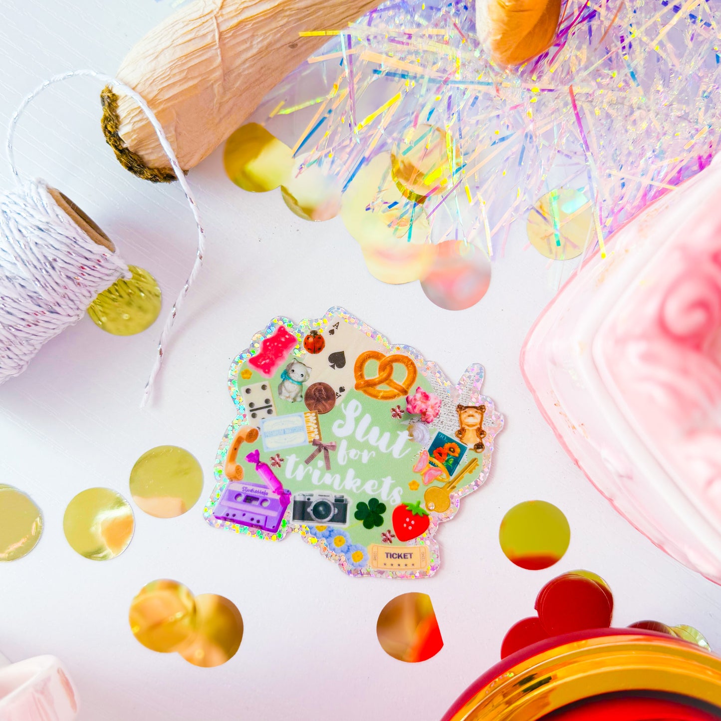 Colorful craft supplies including a wooden mallet, beads, and a decorative sticker on a white background.