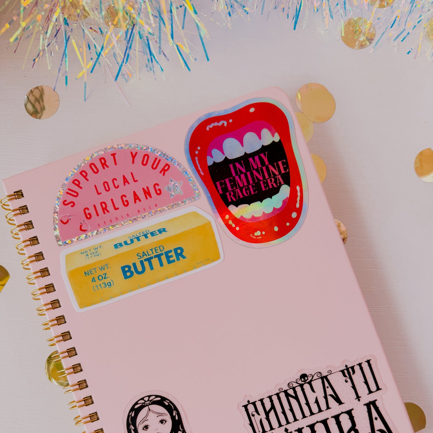 Pink notebook with stickers on a white background with gold confetti