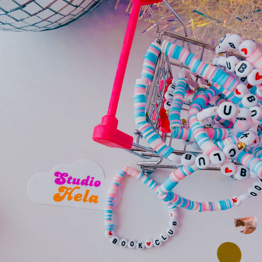 Colorful beaded headbands in a small shopping cart with 'Studio Hela' label on a white background