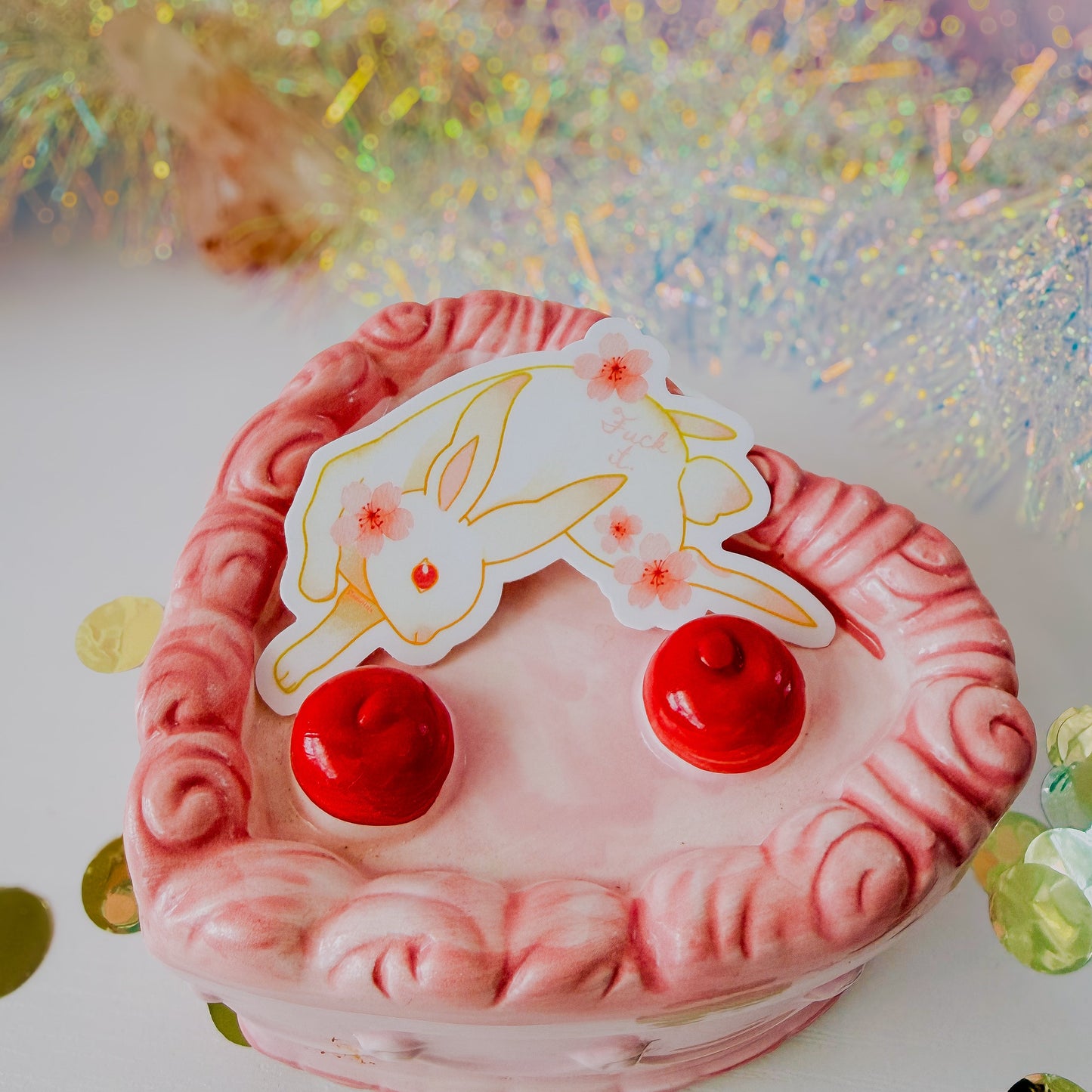 Pink decorative item with red accents and a white label featuring a rabbit design on a glittery background.