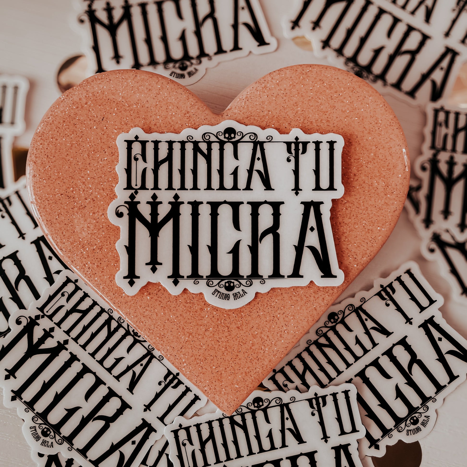 Heart-shaped sticker with 'Chiná tu micra' text surrounded by similar stickers on a light background