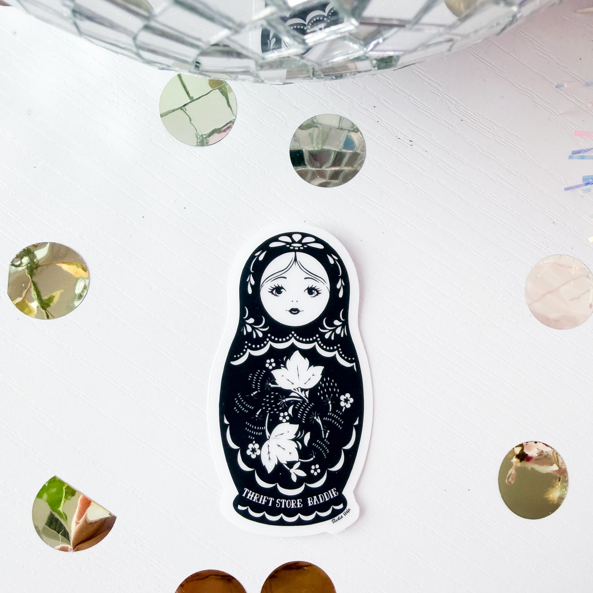 Sticker of a matryoshka doll with floral design on a white surface with decorative elements.