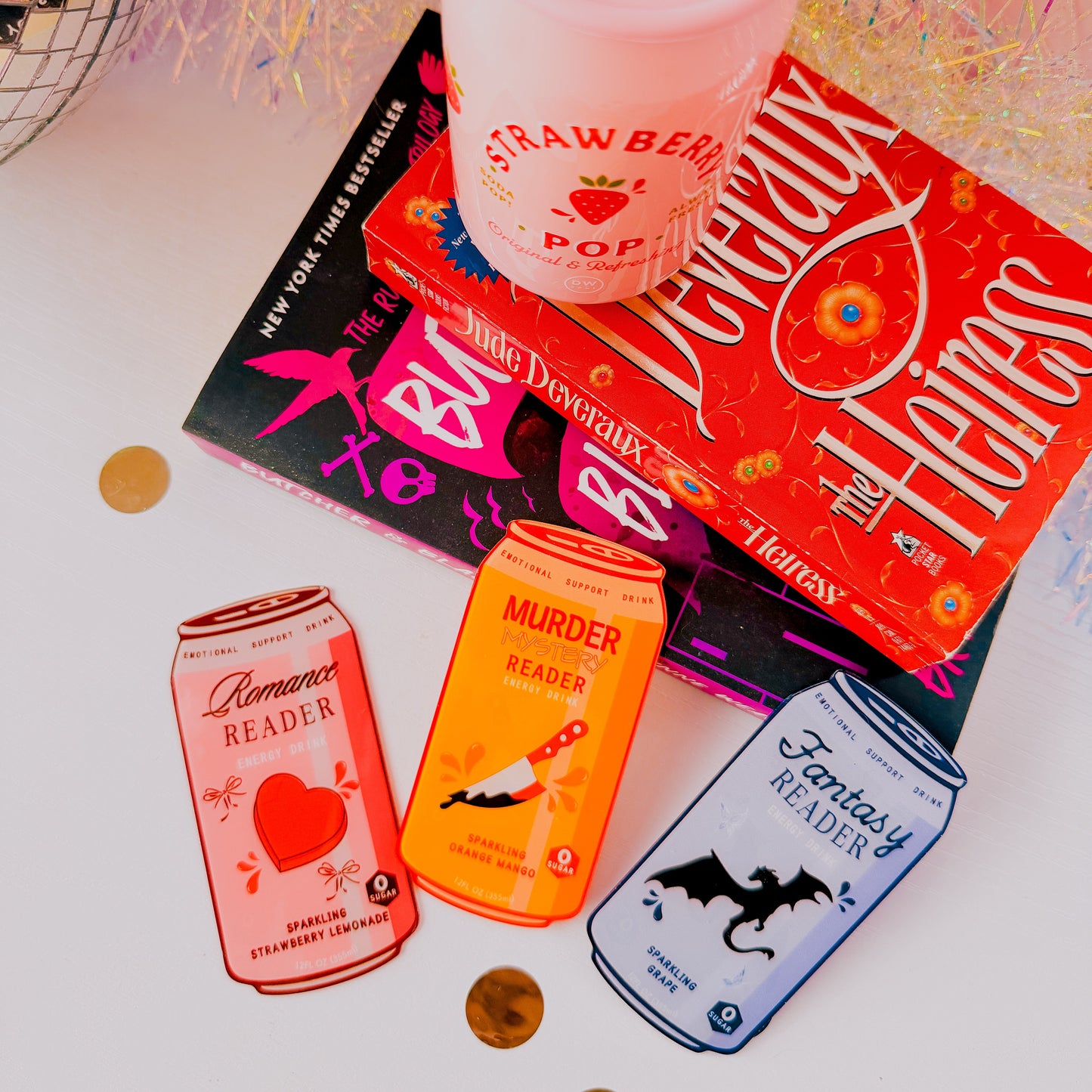 Stack of books with colorful covers and a pink cup on a white surface.