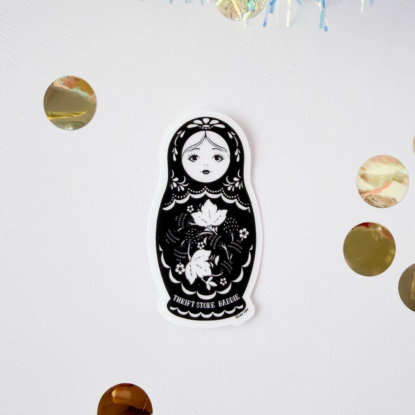 Sticker of a black and white matryoshka doll with floral design on a white background with decorative elements.