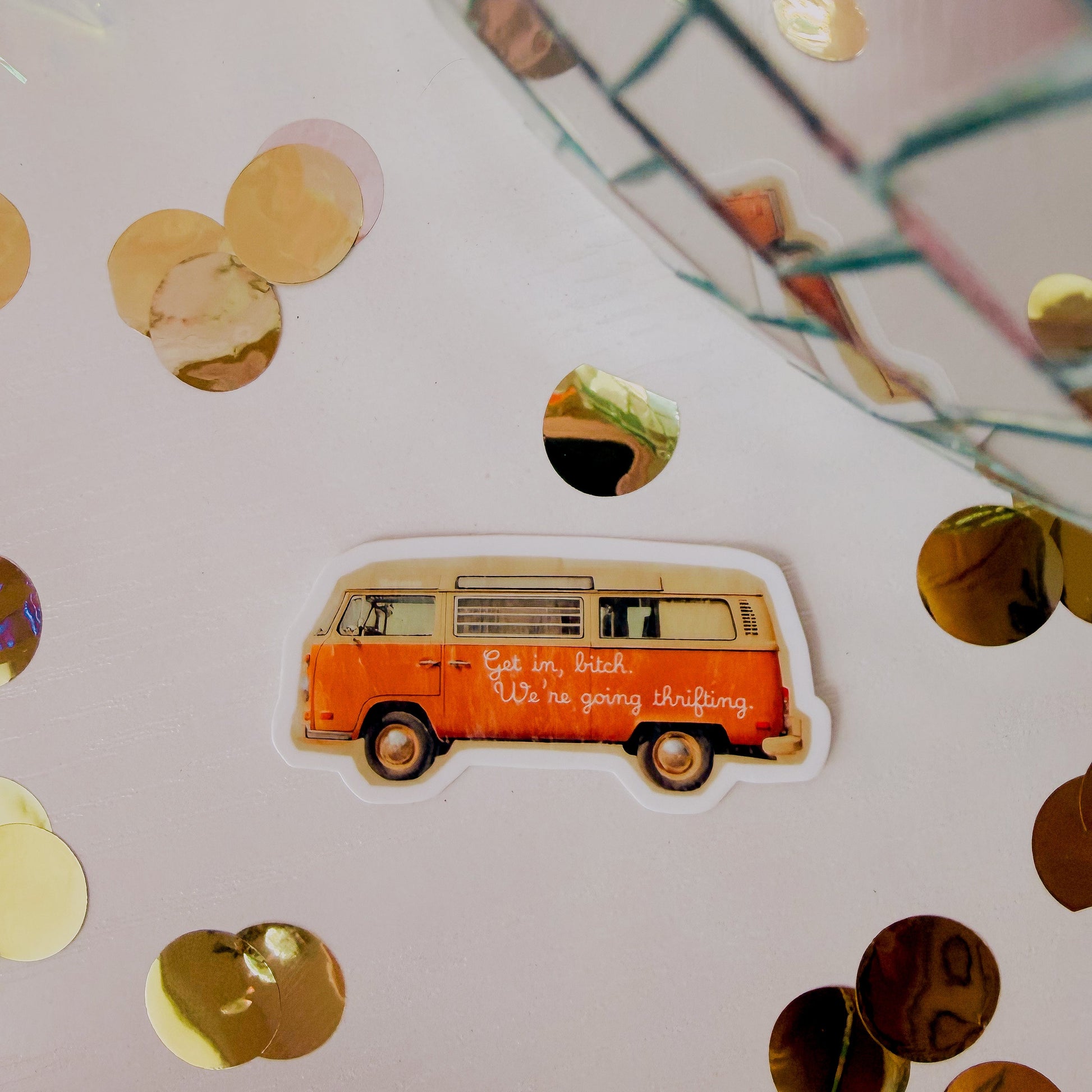 Sticker of a vintage van on a surface with gold confetti