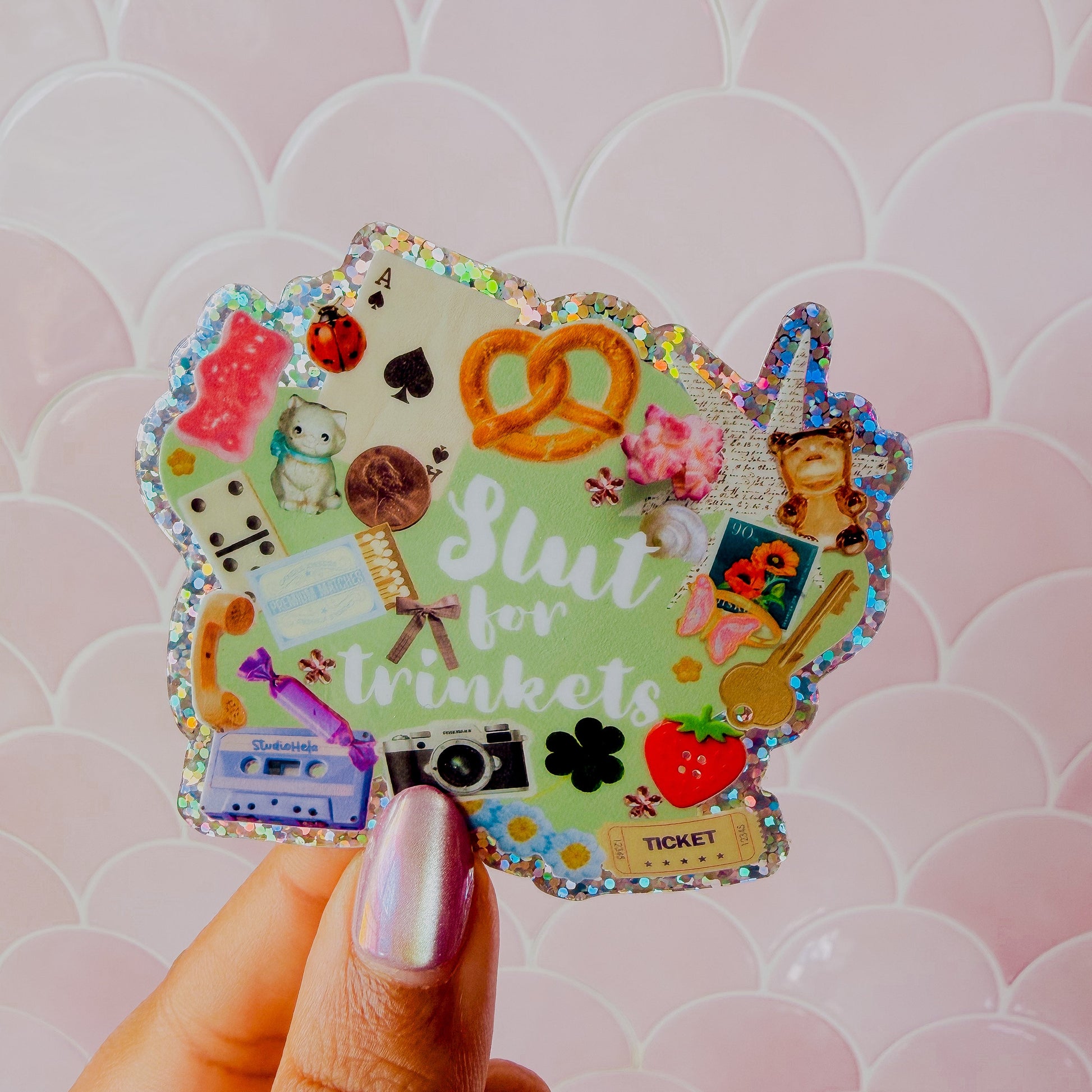 Decorative sticker with various designs held by a hand against a pink patterned background
