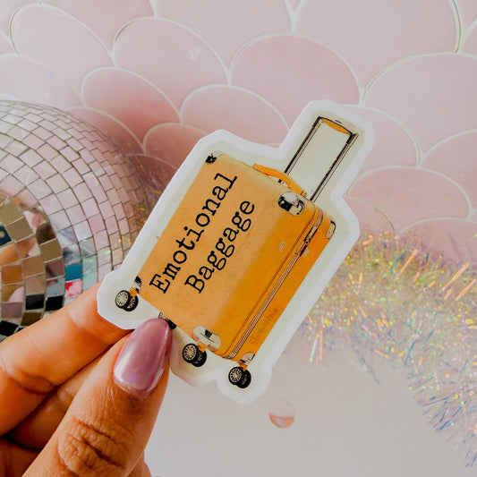 Card with 'Emotional Baggage' text held by a hand against a decorative background