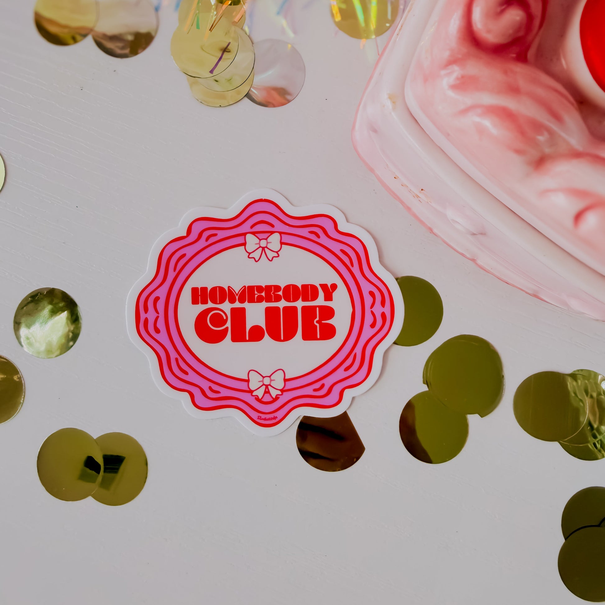Sticker with 'Homebody Club' text on a colorful background with confetti